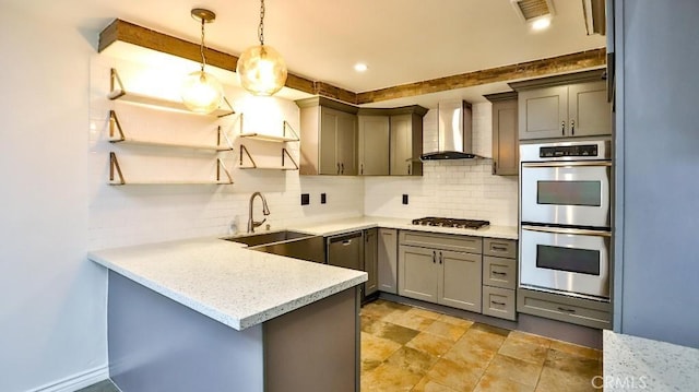 kitchen featuring wall chimney range hood, double oven, a sink, gas stovetop, and gray cabinets