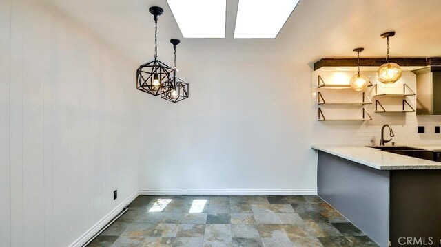 unfurnished dining area featuring a sink, baseboards, and dark stone finish flooring