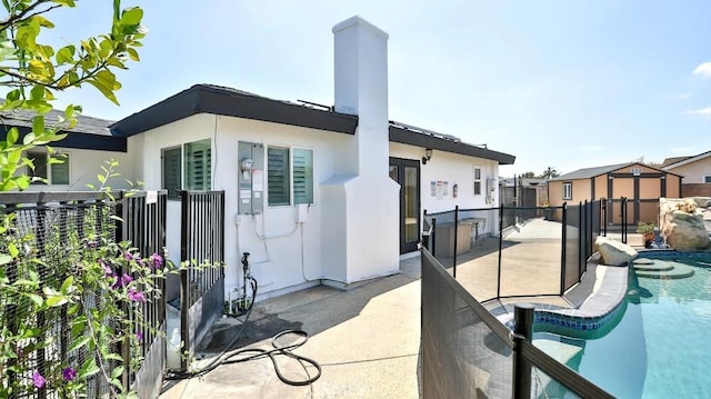 back of property featuring stucco siding, fence, a patio area, and a chimney