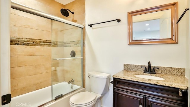 full bath featuring toilet, shower / bath combination with glass door, and vanity