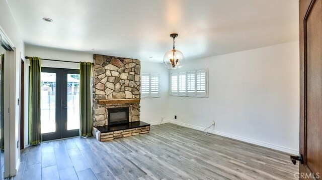 unfurnished living room with french doors, healthy amount of natural light, wood finished floors, and baseboards