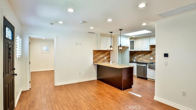 kitchen with stainless steel dishwasher, a peninsula, white cabinetry, tasteful backsplash, and baseboards
