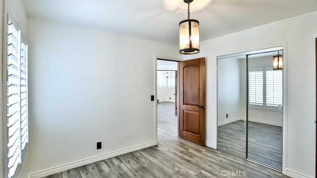 unfurnished bedroom with a closet, wood finished floors, and baseboards