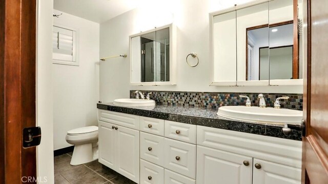 bathroom featuring tile patterned flooring, toilet, double vanity, and decorative backsplash