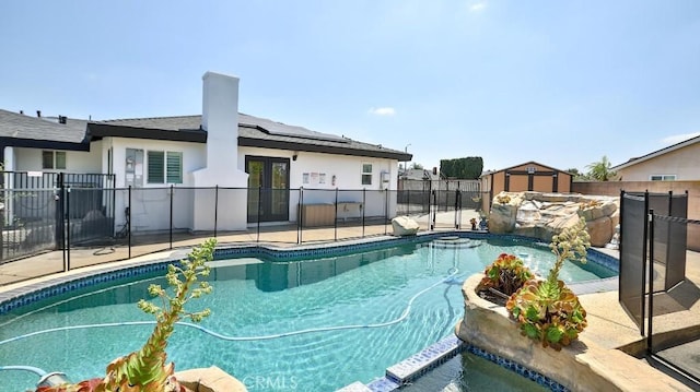 view of pool featuring french doors, a storage unit, a fenced backyard, and a patio area