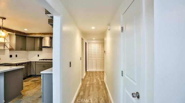 corridor with recessed lighting, baseboards, a sink, and light wood finished floors