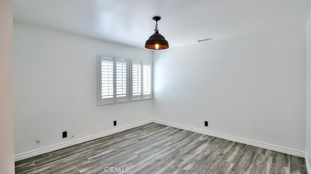 spare room featuring wood finished floors and baseboards