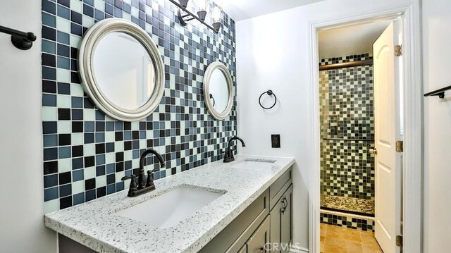 bathroom with a shower stall, backsplash, double vanity, and tile patterned floors