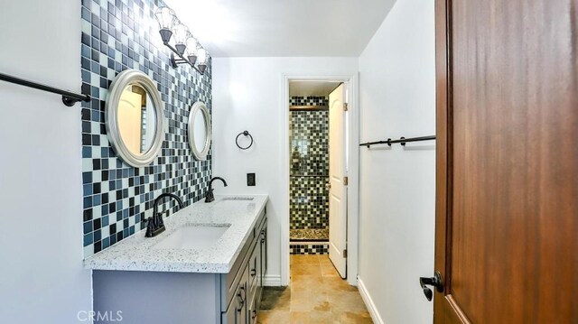 full bath with backsplash, a stall shower, and double vanity
