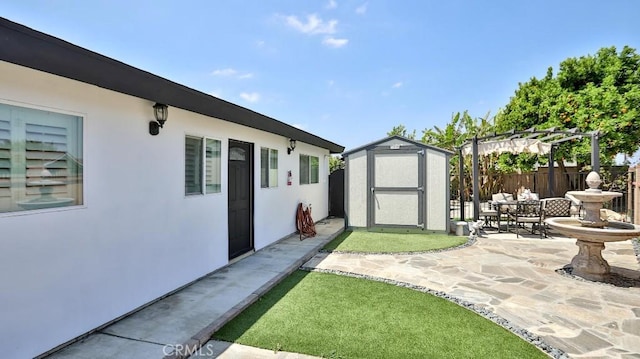 view of yard featuring a patio, fence, a shed, and an outbuilding
