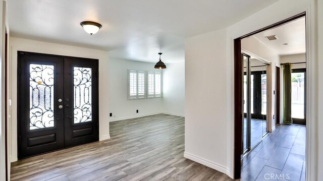 foyer entrance with french doors, baseboards, and wood finished floors