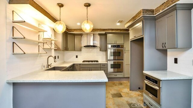 kitchen featuring gray cabinets, wall chimney range hood, stainless steel double oven, a sink, and black stovetop