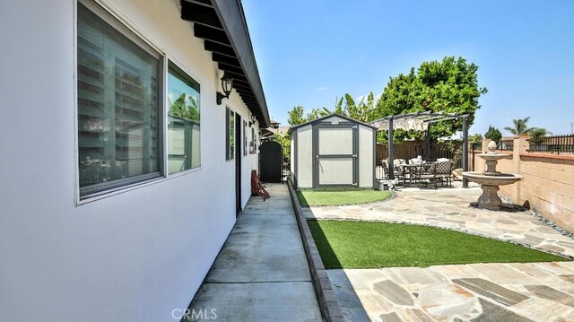 view of yard with a shed, fence, a patio area, an outdoor structure, and a pergola