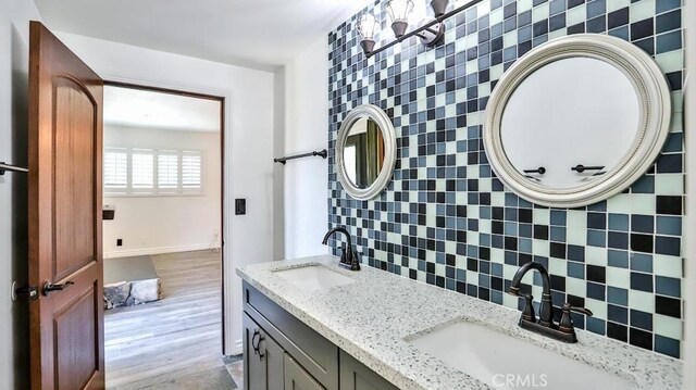 bathroom featuring double vanity, backsplash, and baseboards
