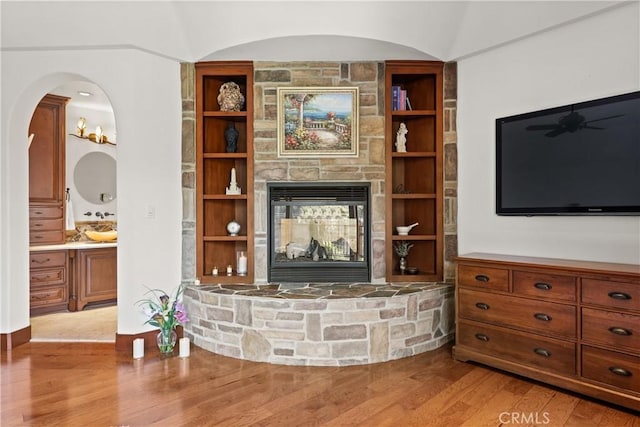 4117 Vanetta Pl, Studio City, CA 91604 - living room featuring light wood-type flooring, ceiling fan, a stone fireplace, and built in shelves