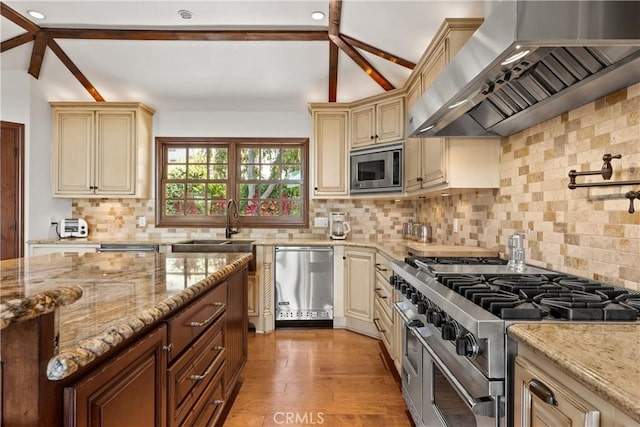 4117 Vanetta Pl, Studio City, CA 91604 - kitchen with wall chimney exhaust hood, cream cabinetry, appliances with stainless steel finishes, light stone countertops, and recessed lighting