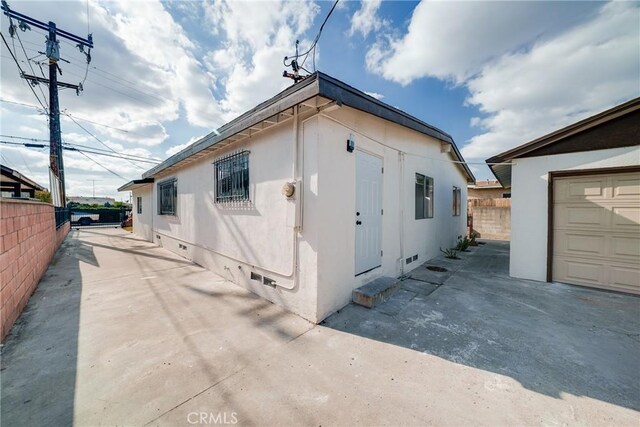 view of property exterior with fence, crawl space, and stucco siding