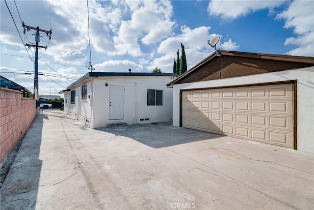 view of front of property with stucco siding, a garage, and fence