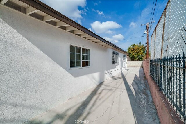 view of property exterior with stucco siding and fence