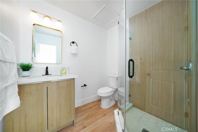 bathroom featuring toilet, a shower stall, vanity, wood finished floors, and baseboards