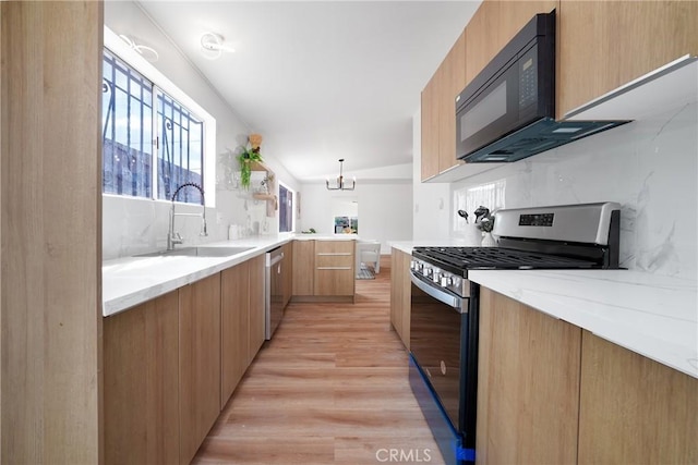 kitchen with appliances with stainless steel finishes, modern cabinets, a sink, and light wood-style floors