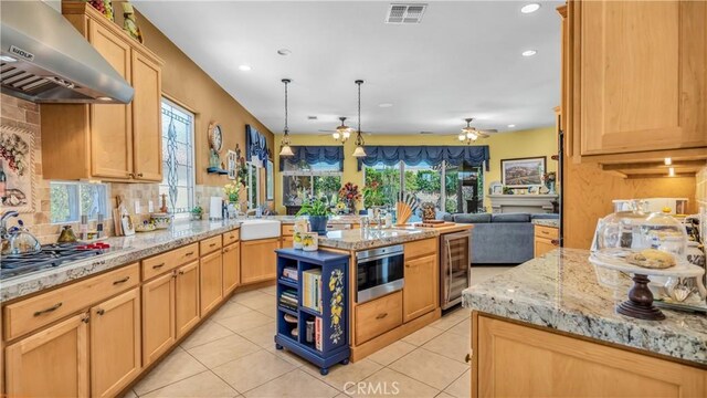74078 W Petunia Pl, Palm Desert, CA 92211 - kitchen with wall chimney range hood, beverage cooler, open floor plan, stainless steel gas cooktop, and a ceiling fan
