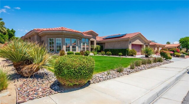 74078 W Petunia Pl, Palm Desert, CA 92211 - view of front of house featuring stucco siding, roof mounted solar panels, a tile roof, and a garage