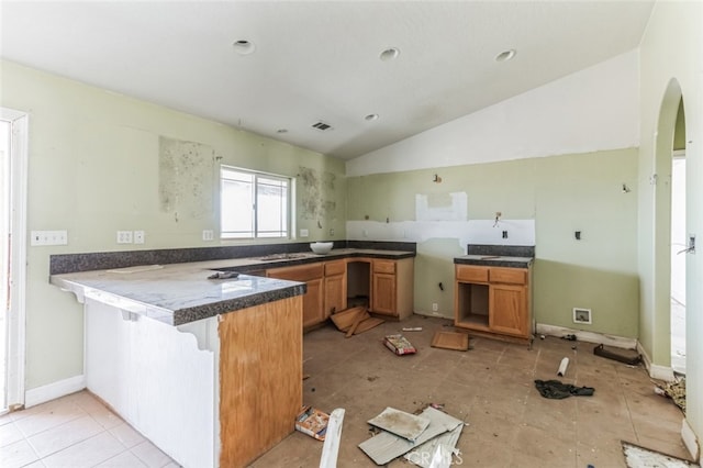 8975 Pumalo Rd, Lucerne Valley, CA 92356 - kitchen featuring a peninsula, arched walkways, lofted ceiling, a breakfast bar, and dark countertops