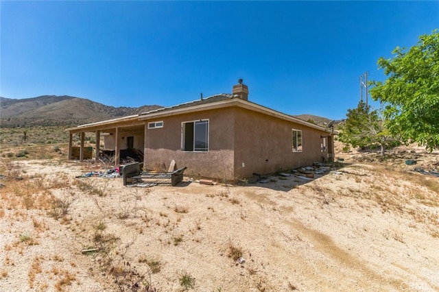 8975 Pumalo Rd, Lucerne Valley, CA 92356 - back of property with a mountain view, a chimney, and stucco siding