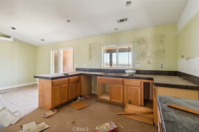 8975 Pumalo Rd, Lucerne Valley, CA 92356 - kitchen with brown cabinetry, a peninsula, light tile patterned floors, and dark countertops