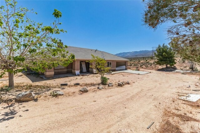 8975 Pumalo Rd, Lucerne Valley, CA 92356 - rear view of house featuring dirt driveway, a mountain view, an attached garage, and a tile roof
