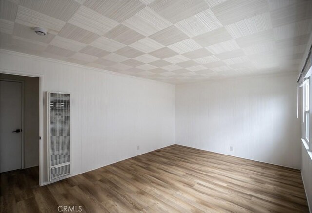 spare room featuring a heating unit, wood finished floors, ornamental molding, and a smoke detector