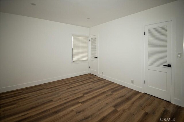 unfurnished room featuring dark wood-style flooring and baseboards