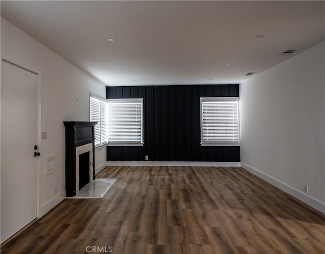 unfurnished living room with wood finished floors, baseboards, and a fireplace