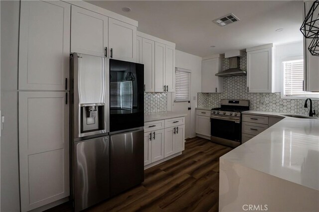 kitchen with stainless steel appliances, wall chimney exhaust hood, a sink, and backsplash