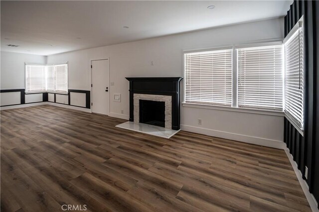 unfurnished living room with dark wood-style floors, a high end fireplace, and baseboards