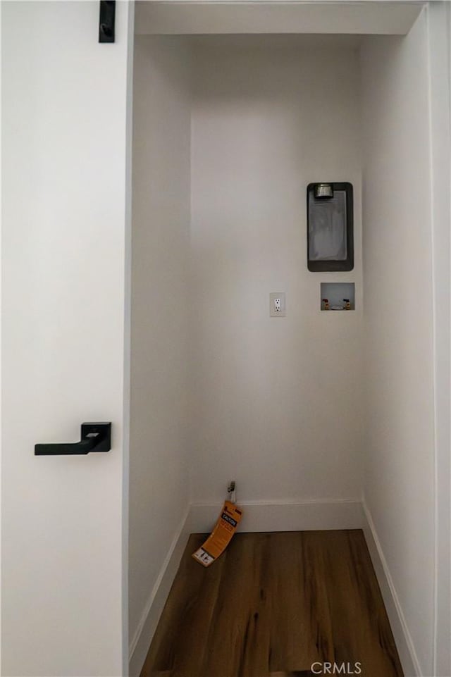 clothes washing area featuring baseboards, wood finished floors, and washer hookup