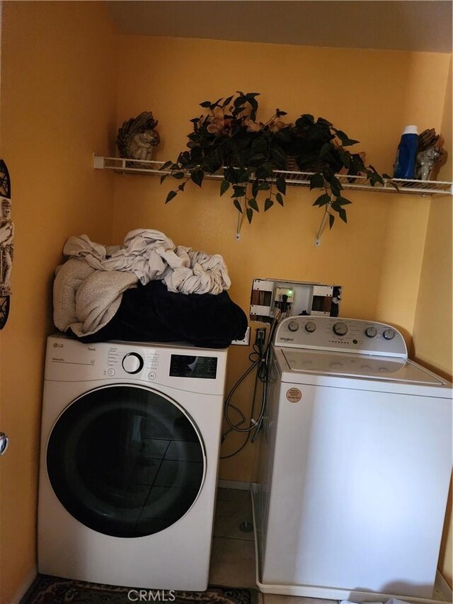 laundry area featuring washing machine and dryer and tile patterned flooring