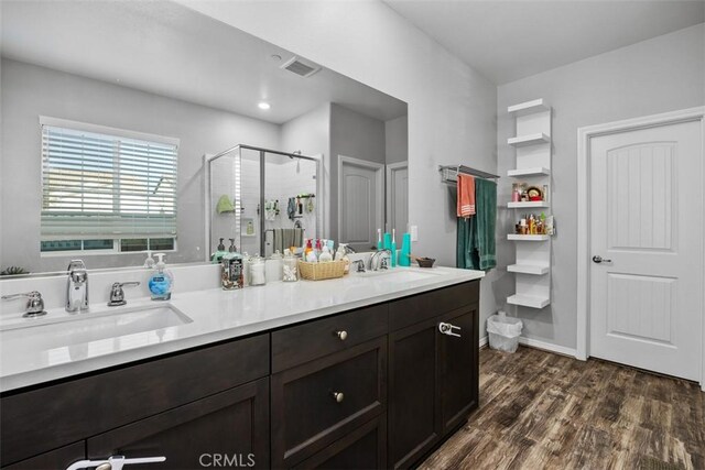 bathroom featuring a shower stall, wood finished floors, and double vanity