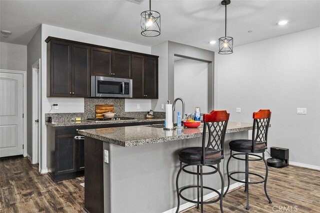 kitchen with appliances with stainless steel finishes, dark wood finished floors, baseboards, hanging light fixtures, and recessed lighting