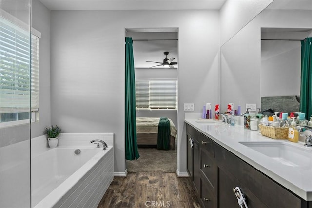 bathroom with connected bathroom, wood finished floors, ceiling fan, a bath, and double vanity