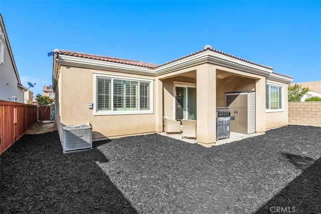rear view of house with stucco siding, a fenced backyard, cooling unit, a tiled roof, and a patio area