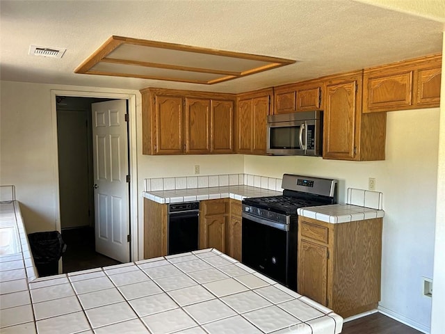 14402 Boxtree St, Lake Hughes, CA 93532 - kitchen featuring stainless steel appliances, tile countertops, and brown cabinets