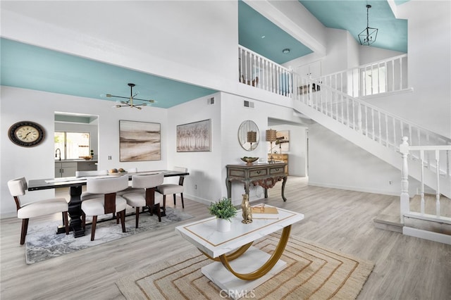 24071 Orange Creek Cir, Moreno Valley, CA 92557 - living room featuring a chandelier, wood finished floors, baseboards, stairs, and a high ceiling