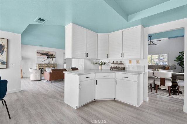 24071 Orange Creek Cir, Moreno Valley, CA 92557 - kitchen with light countertops, open floor plan, white cabinetry, light wood finished floors, and a towering ceiling