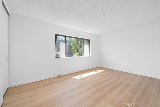 1622 Iowa St Unit A, Costa Mesa, CA 92626 - spare room featuring a textured ceiling, light wood-style floors, and baseboards