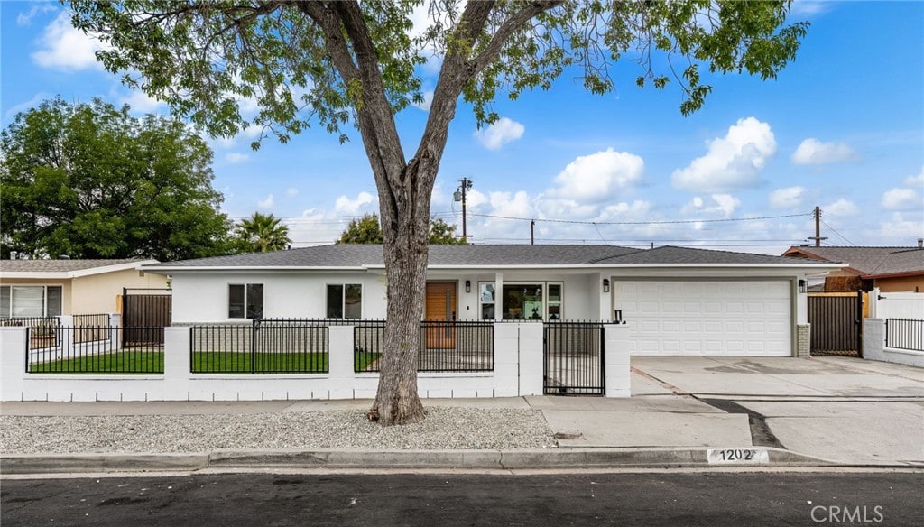 1202 N Gates St, Santa Ana, CA 92703 - ranch-style house with a garage, driveway, a fenced front yard, and stucco siding