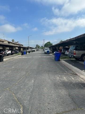 view of asphalt road with street lights, sidewalks, and curbs
