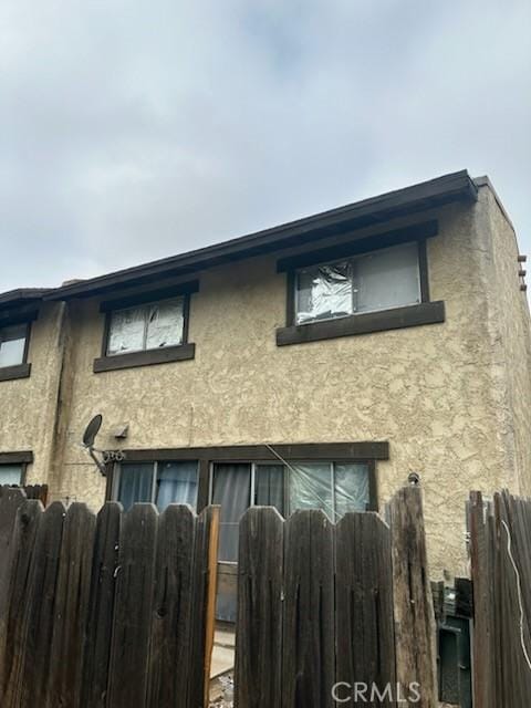 view of front facade with stucco siding and fence