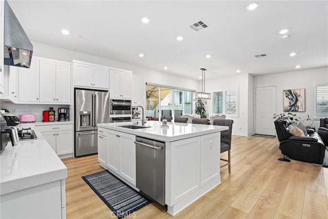 27120 Purple Sage Ct, Valencia, CA 91381 - kitchen with appliances with stainless steel finishes, wall chimney range hood, a sink, light countertops, and white cabinetry